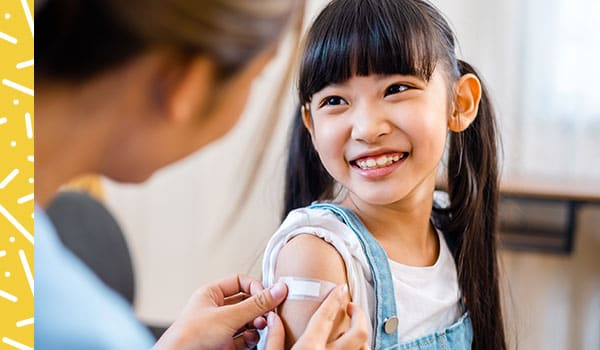 Doctor applying bandage to injection site on child's upper arm.