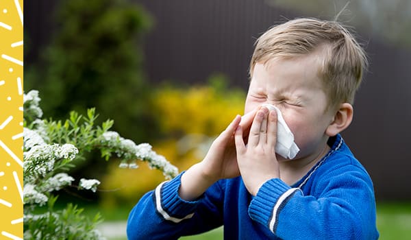 A little boy sneezing into tissue.