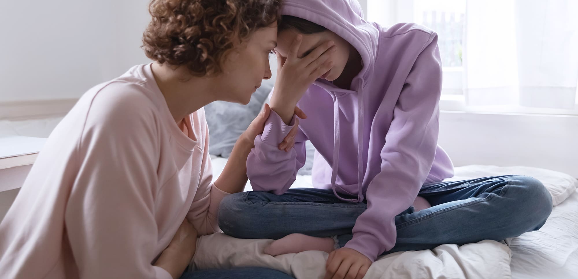 Mother consoling teen who is showing signs of depression.